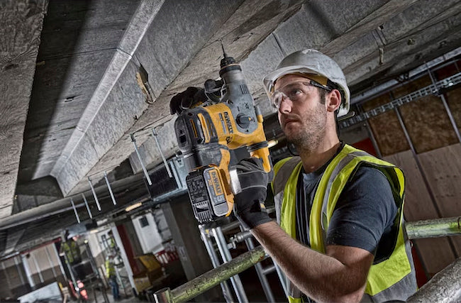 Ein Mann bohrt ein Loch in die Decke senkrecht nach oben mit einem Dewalt DCH283NT 18 Volt SDS-plus Akku-Kombihammer 26mm (bürstenlos