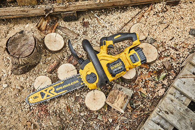 Eine Dewalt DCM565N 18 Volt Akku-Kettensäge liegt in Sägespäne auf dem Waldboden