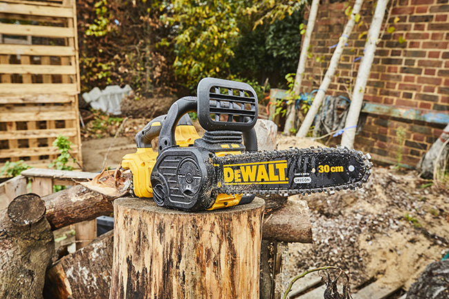 Eine DCM565N 18 Volt Akku-Kettensäge liegt auf einem frisch geschnittenem Baumstumpf Dewalt 